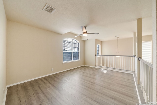 unfurnished room with hardwood / wood-style floors, ceiling fan with notable chandelier, and a textured ceiling