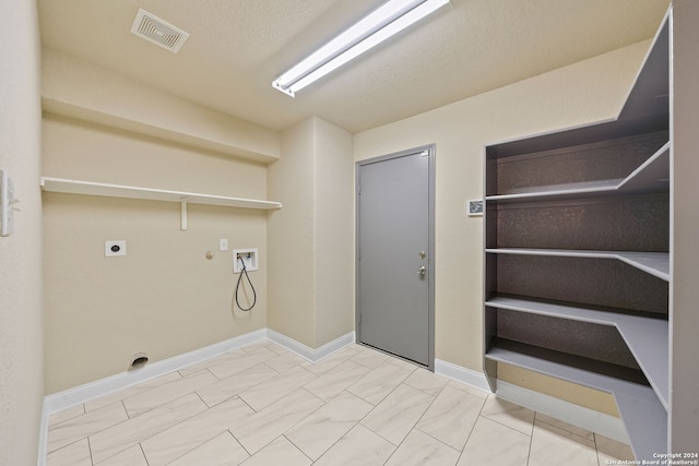 clothes washing area featuring hookup for a washing machine, electric dryer hookup, a textured ceiling, and gas dryer hookup