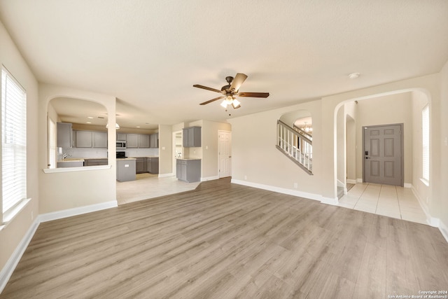 unfurnished living room with a textured ceiling, light hardwood / wood-style floors, and ceiling fan