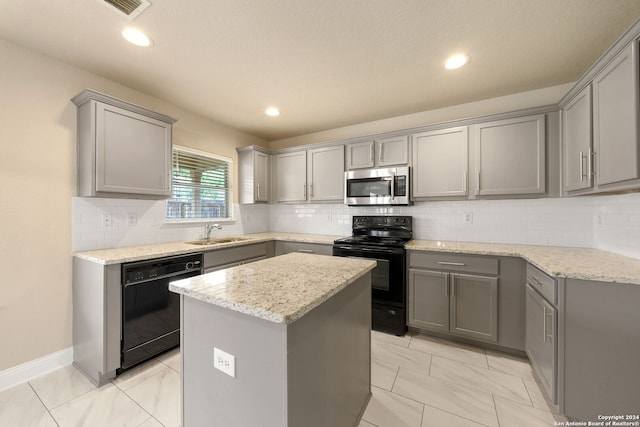 kitchen featuring gray cabinetry, black appliances, and a center island