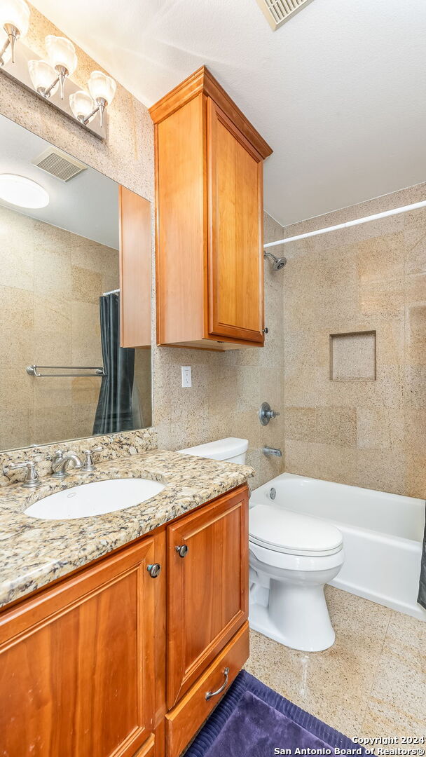 full bathroom with toilet, vanity, shower / bath combo with shower curtain, and tile walls