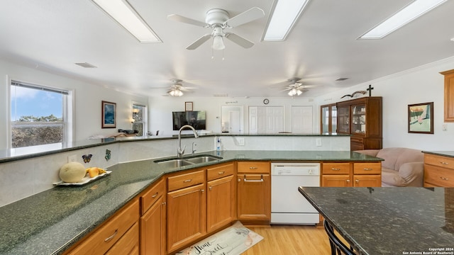 kitchen featuring dark stone counters, dishwasher, sink, ornamental molding, and light wood-type flooring