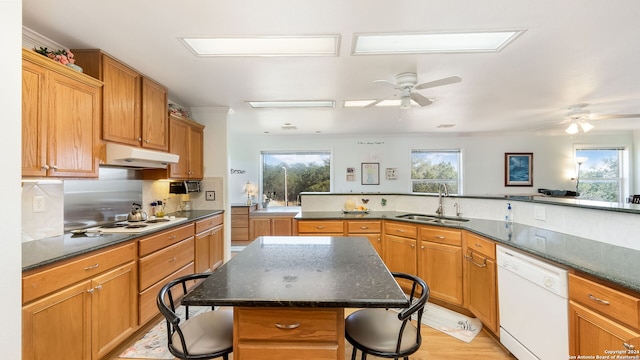 kitchen with light hardwood / wood-style floors, sink, a kitchen island, a breakfast bar, and white appliances