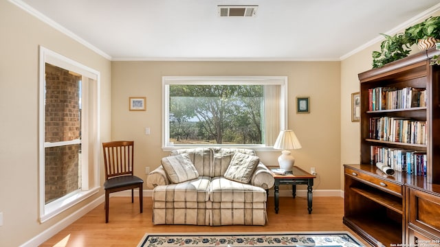 sitting room with light wood-type flooring and crown molding