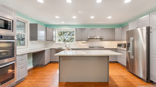 kitchen featuring stainless steel appliances, gray cabinets, light wood-type flooring, and a kitchen island