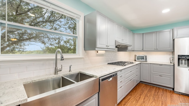 kitchen featuring light wood-type flooring, stainless steel appliances, sink, and backsplash