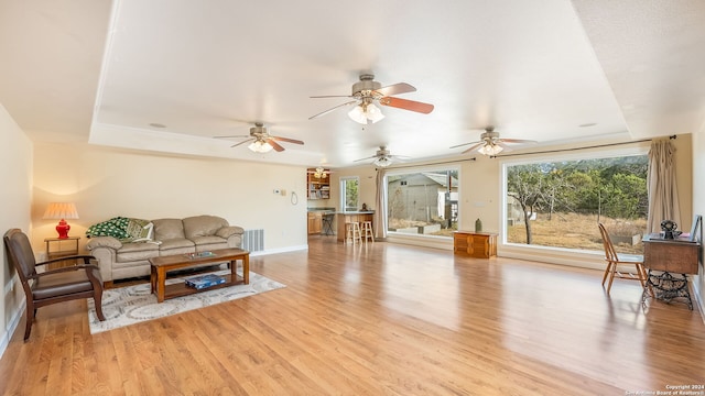 living room featuring light wood-type flooring and a tray ceiling