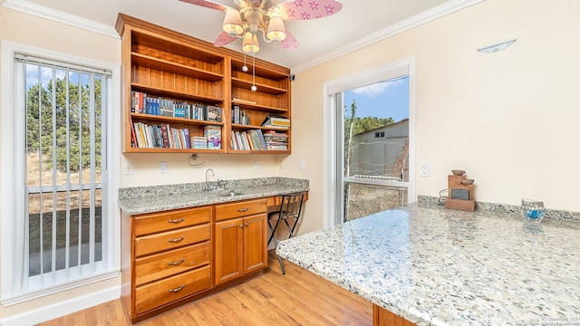 kitchen with light stone countertops, sink, light hardwood / wood-style flooring, and ornamental molding