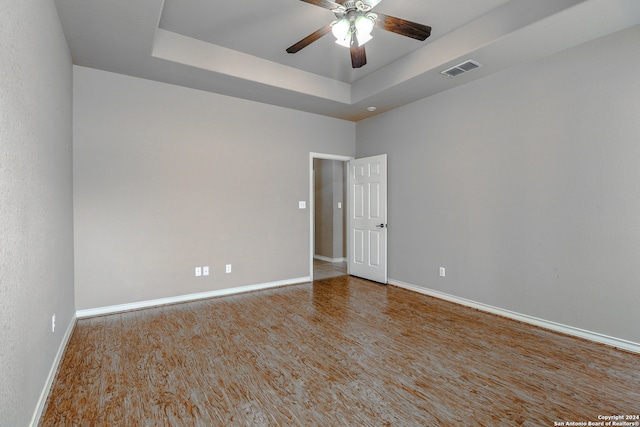 unfurnished room featuring hardwood / wood-style flooring, a raised ceiling, and ceiling fan