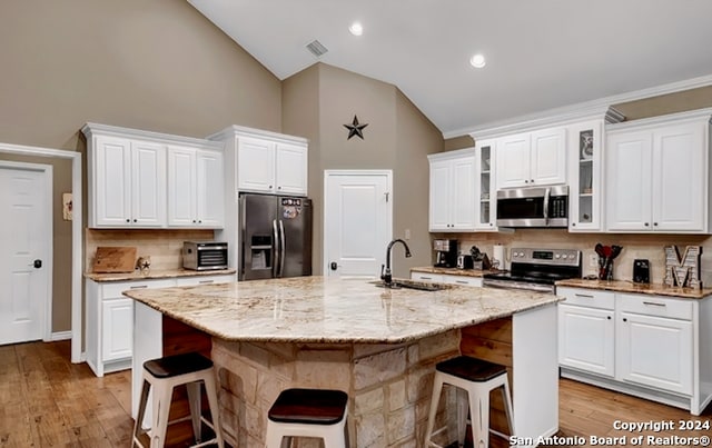 kitchen featuring a center island with sink, white cabinetry, appliances with stainless steel finishes, sink, and light hardwood / wood-style flooring