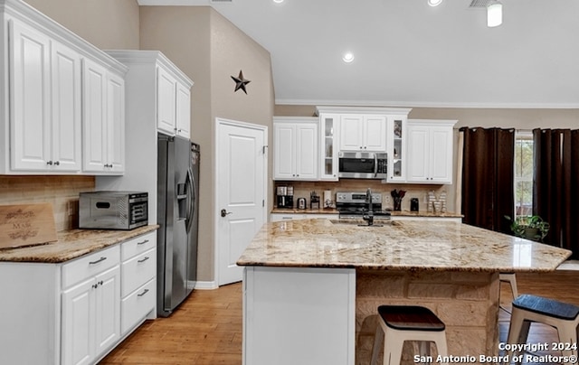 kitchen with white cabinetry, appliances with stainless steel finishes, a center island with sink, and light hardwood / wood-style flooring