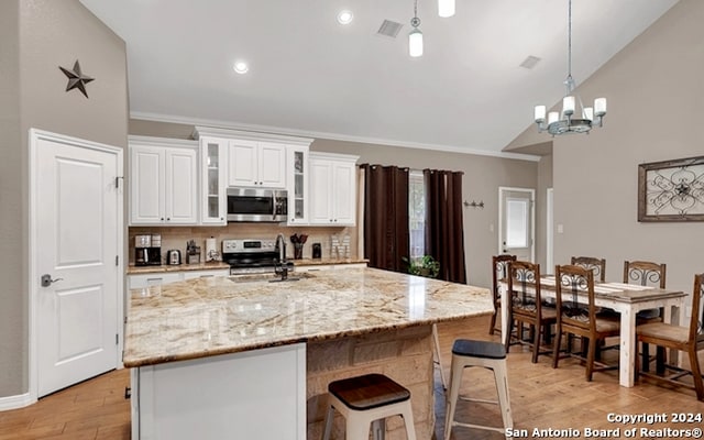 kitchen with light wood-type flooring, appliances with stainless steel finishes, lofted ceiling, and sink