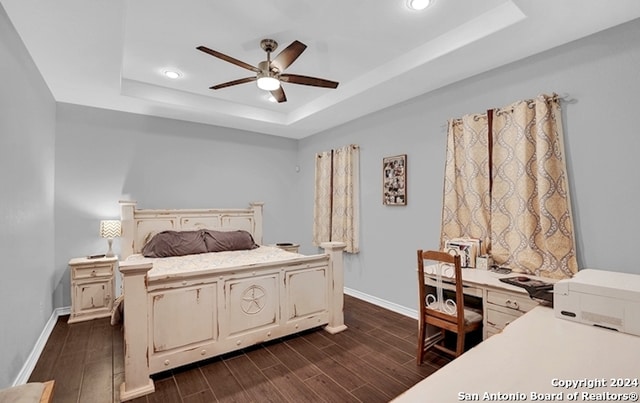 bedroom featuring dark wood-type flooring, ceiling fan, and a tray ceiling