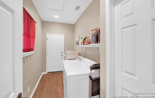 laundry room featuring washing machine and clothes dryer and light hardwood / wood-style flooring