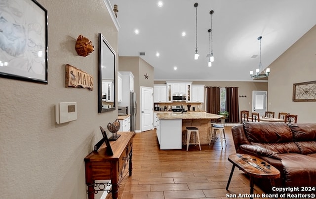 living room featuring high vaulted ceiling, an inviting chandelier, and wood-type flooring