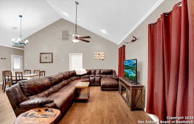 living room with light wood-type flooring, ceiling fan with notable chandelier, crown molding, and high vaulted ceiling