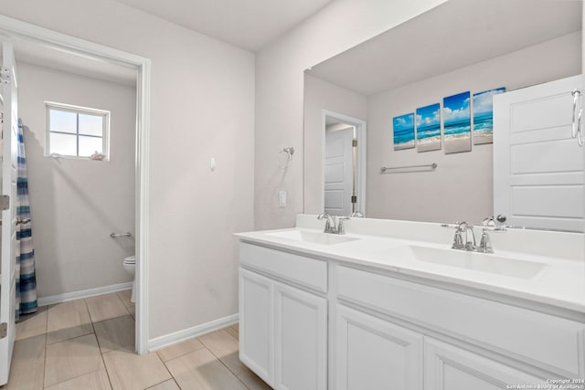 bathroom with toilet, vanity, and tile patterned floors