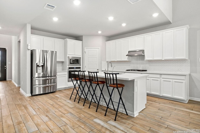 kitchen featuring stainless steel appliances, white cabinetry, and a kitchen island with sink