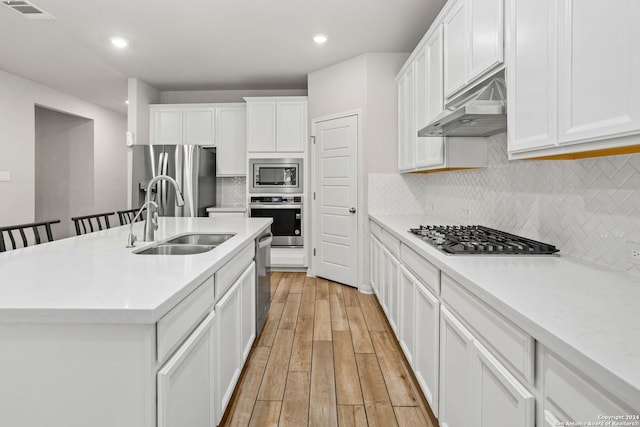 kitchen featuring white cabinetry, appliances with stainless steel finishes, sink, an island with sink, and light hardwood / wood-style flooring