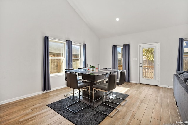 dining room featuring light wood-type flooring and high vaulted ceiling