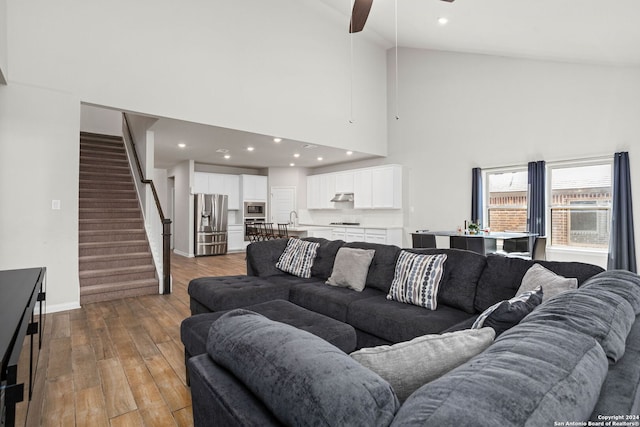 living room with high vaulted ceiling, light hardwood / wood-style floors, ceiling fan, and sink