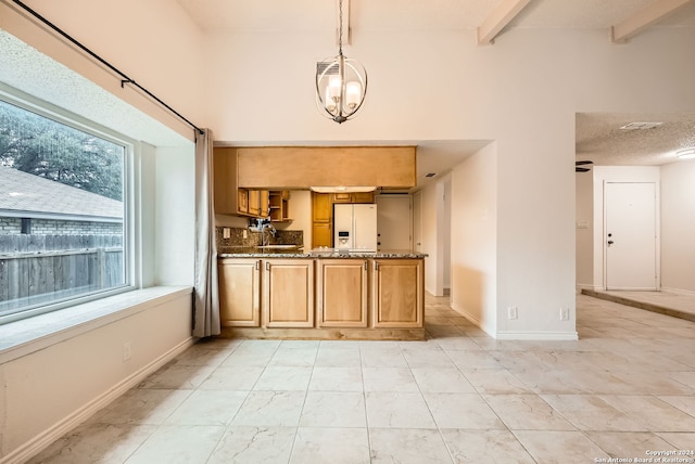 kitchen with hanging light fixtures, an inviting chandelier, white refrigerator with ice dispenser, dark stone counters, and a textured ceiling