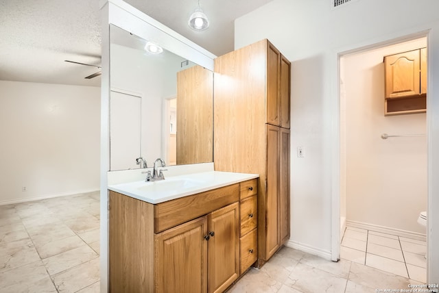 bathroom with ceiling fan, vanity, a textured ceiling, and toilet