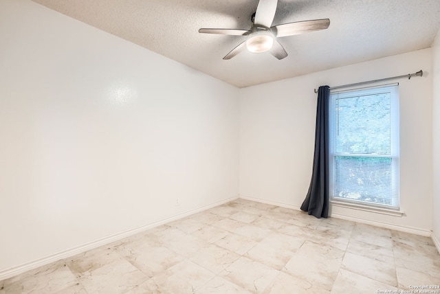 unfurnished room with ceiling fan and a textured ceiling