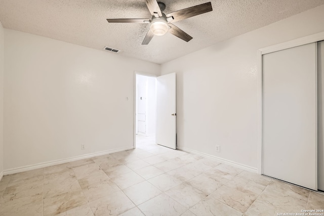 unfurnished bedroom with ceiling fan, a closet, and a textured ceiling