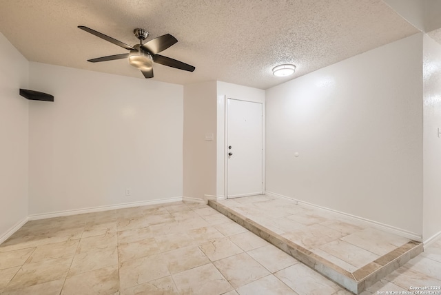 empty room featuring ceiling fan and a textured ceiling