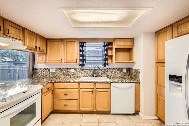 kitchen with a textured ceiling, white appliances, sink, light tile patterned floors, and dark stone countertops