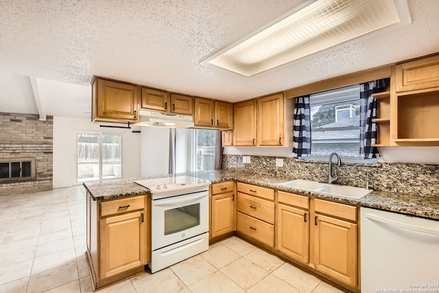 kitchen with a textured ceiling, sink, a healthy amount of sunlight, and white appliances