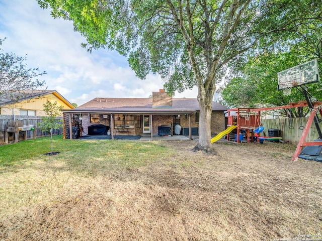 rear view of house featuring a playground and a yard