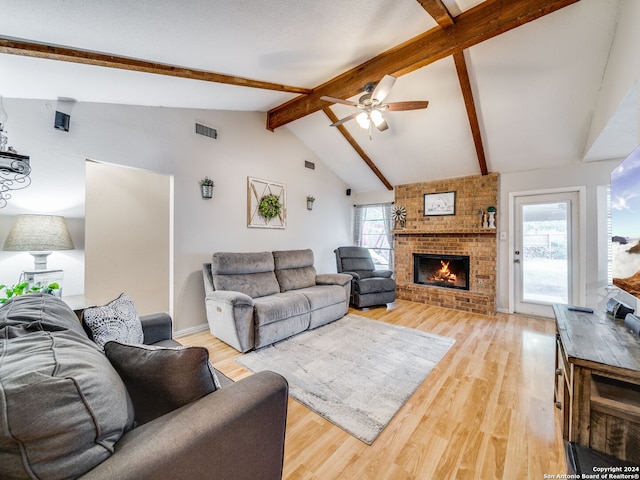 living room featuring light wood-type flooring, a wealth of natural light, vaulted ceiling with beams, and a fireplace