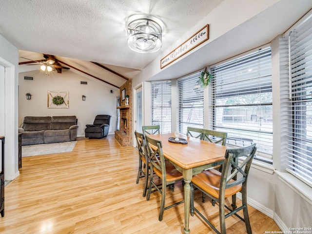 dining space with a textured ceiling, vaulted ceiling, ceiling fan, and light hardwood / wood-style flooring