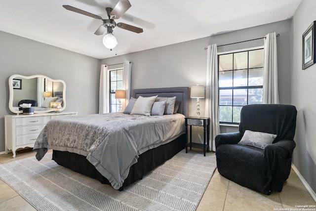 tiled bedroom with ceiling fan and multiple windows