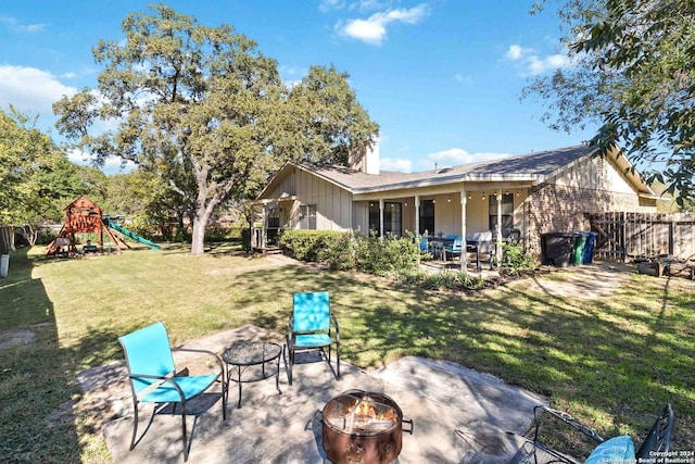 rear view of property with a playground, a fire pit, a patio area, and a lawn