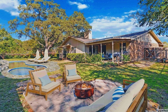 back of house featuring a patio, an outdoor living space with a fire pit, and a lawn