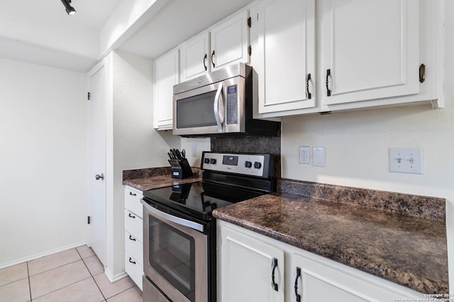 kitchen featuring light tile patterned floors, white cabinetry, dark stone countertops, and appliances with stainless steel finishes