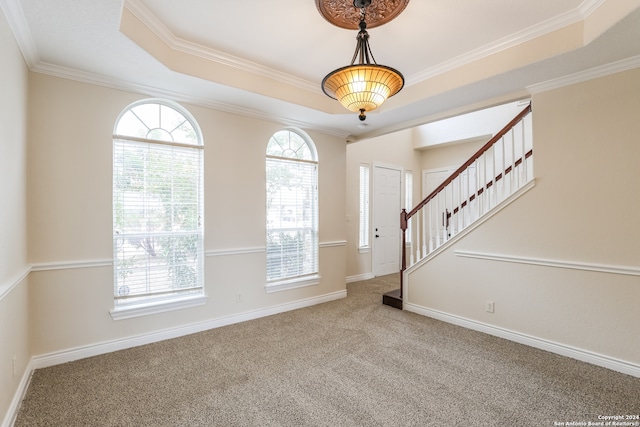 entryway with a raised ceiling, crown molding, and carpet floors