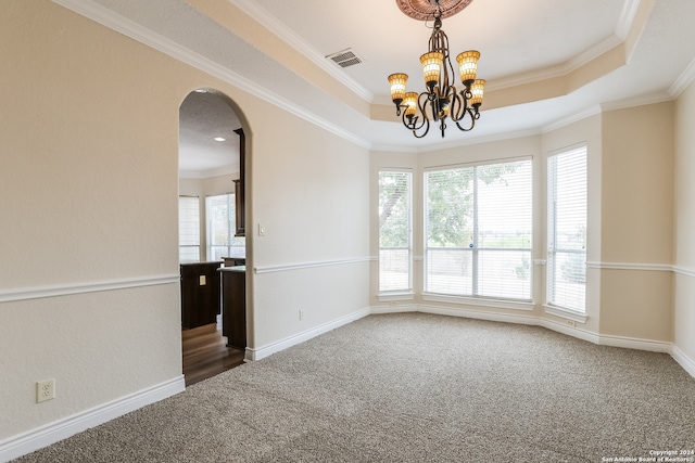 carpeted spare room with crown molding, a tray ceiling, and an inviting chandelier