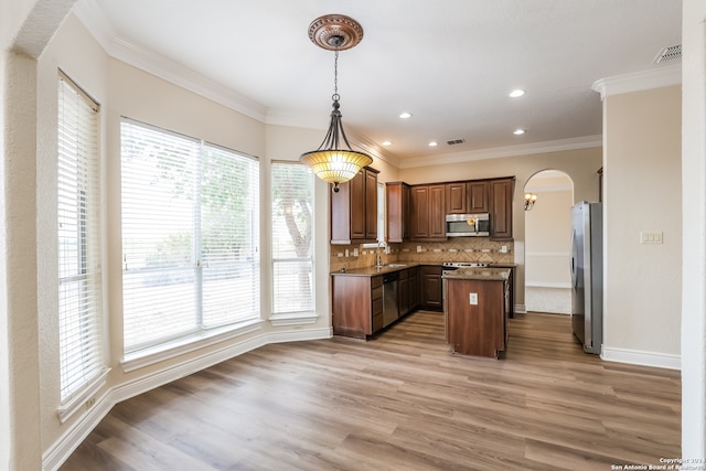 kitchen with a center island, hanging light fixtures, a healthy amount of sunlight, and stainless steel appliances