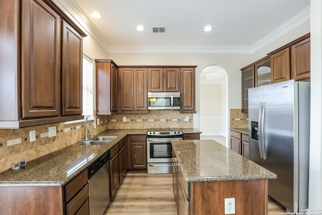 kitchen with crown molding, stainless steel appliances, sink, dark stone countertops, and a center island