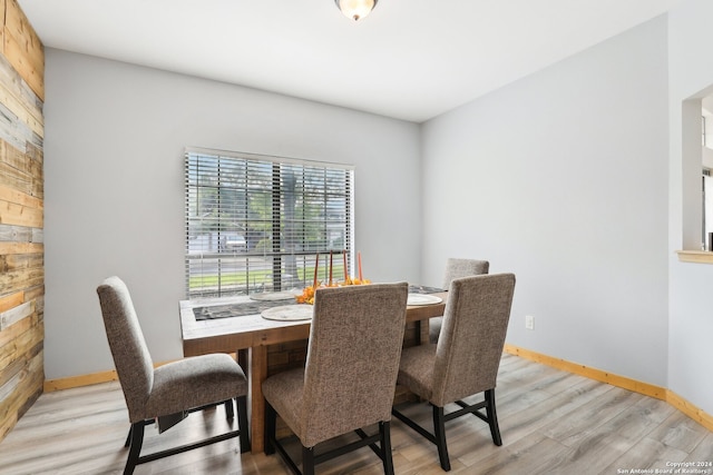 dining area with light hardwood / wood-style floors and wooden walls