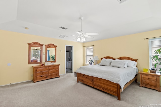 bedroom featuring ensuite bathroom, light carpet, and ceiling fan