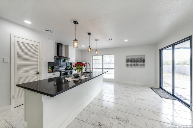 kitchen with a center island with sink, white cabinets, wall chimney exhaust hood, stainless steel electric stove, and pendant lighting