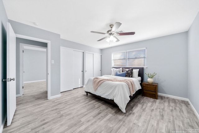 bedroom with multiple closets, ceiling fan, and light hardwood / wood-style flooring