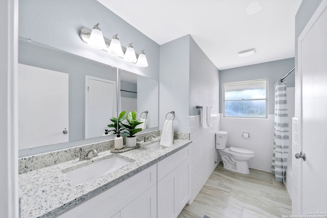 bathroom with tile walls, vanity, and toilet