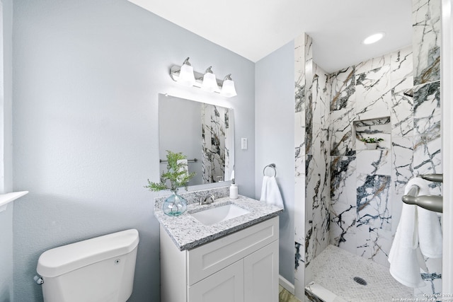 bathroom with vanity, toilet, and tiled shower