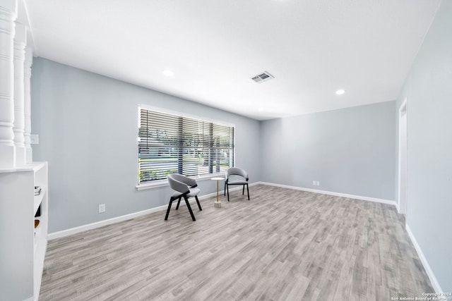 living area with ornate columns and light hardwood / wood-style flooring